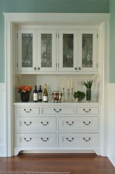 a white china cabinet filled with bottles and glasses