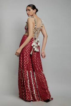 Maroon tassel embellished sleeveless halter neck back tie-up choli with florence multi thread embroidery. Paired with a tassel embellished chevron woven banarasi georgette sharara. - Aza Fashions Elegant Festive Sets With Back Tassel Tie-up, Traditional Wedding Dress With Back Tassel Tie-up, Designer Elegant Sharara With Tassels, Elegant Designer Wear Sharara With Tassels, Festive Fitted Sets With Woven Motifs, Elegant Festive Sets With Woven Motifs, Fitted Wedding Sets With Tassels, Wedding Sets With Tassels And Fitted Design, Sharara For Women