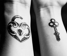 two people with tattoos on their arms holding keys and a heart shaped key to each other