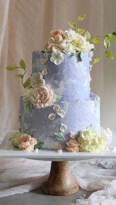 a three layer blue cake with flowers on top