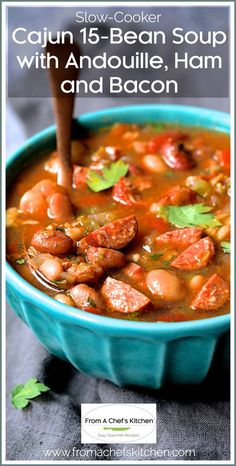 a blue bowl filled with sausage and bean soup on top of a gray tablecloth