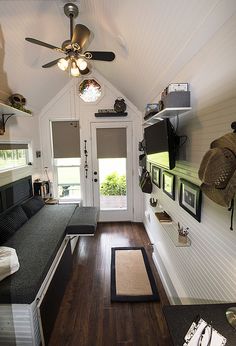 the inside of a tiny house with wood floors and ceiling fans on either side of the door