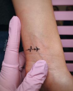 a small heartbeat tattoo on the wrist with an arrow pointing up at it's center