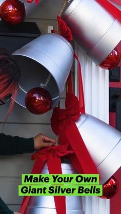 a woman is decorating some bells with red ribbon