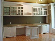 an empty kitchen with white cabinets and wood floors