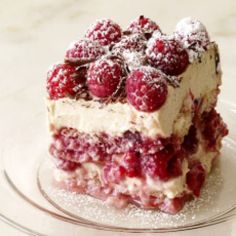 a piece of cake with raspberries on top is sitting on a glass plate