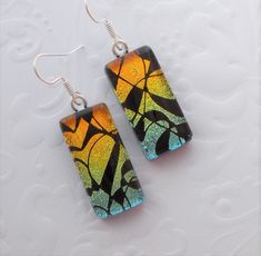 a pair of earrings that have been made to look like stained glass and are sitting on a white surface