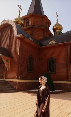 a woman standing in front of a wooden church