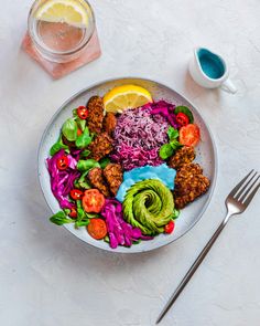 a white plate topped with meat and veggies next to a glass of water