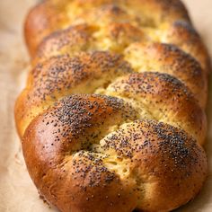 a loaf of bread with poppy seed sprinkled on top sitting on wax paper