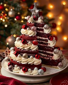 a red velvet cake decorated with white frosting and silver decorations on a plate in front of a christmas tree