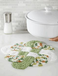 crocheted dishcloths are on the counter next to a white pot holder