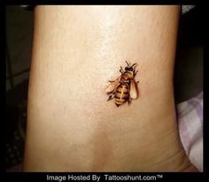 a small bee tattoo on the side of a woman's stomach, with an insect crawling on it