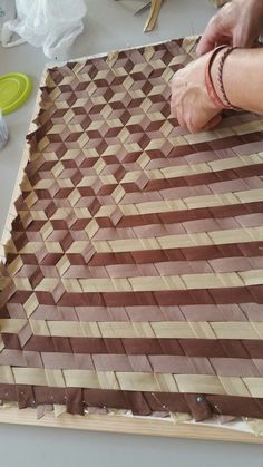 a person is working on something made out of strips of brown and tan paper with scissors