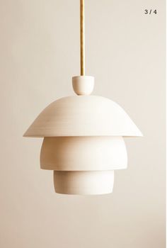 a white light hanging from a ceiling fixture with a wooden stick sticking out of it