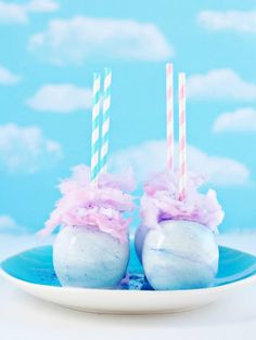 two cake pops with pink and white frosting on them in a blue plate against a sky background