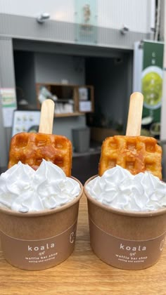 two ice cream sundaes with waffle toppings and whipped cream on top