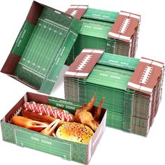 four boxes filled with different types of food on top of a white surface, each containing a football field