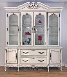 a white china cabinet with glass doors and drawers