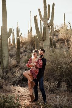 a man and woman dancing in front of cacti