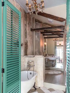 an open door leading to a bathroom with green shutters and chandelier hanging from the ceiling