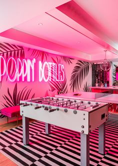 a pink room with foo pong tables and neon lights