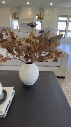 a white vase filled with leaves sitting on top of a table next to a cake