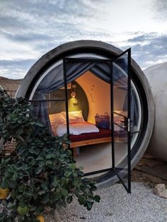 the inside of a tent with a bed in it next to a tree and some plants