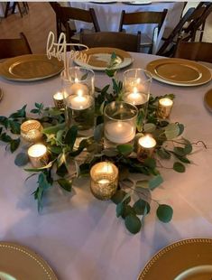 the table is set with candles and greenery