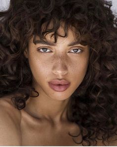 a woman with freckled hair and blue eyes is posing for the camera in front of a white background