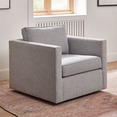 a gray chair sitting on top of a rug in front of a window with a wooden frame