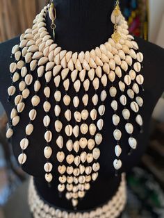 a black mannequin with white shells on it's neck and two necklaces hanging from the back