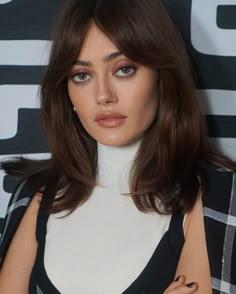 a close up of a person wearing a black and white outfit with long hair in front of a wall