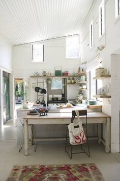 a room with a table, rug and shelves on the wall in front of it