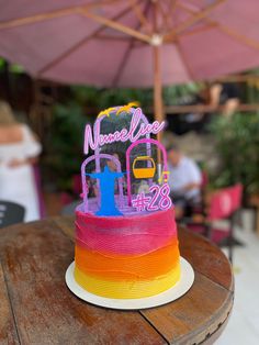 a birthday cake that is on top of a table with an umbrella in the background