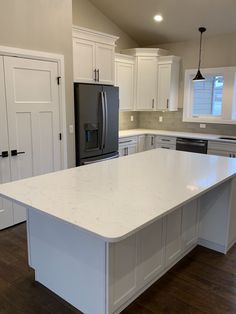 a large white kitchen with an island in the middle and cabinets on both sides,