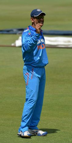 a man standing on top of a green field holding his hand up to his face