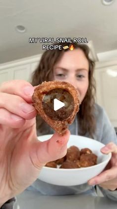 a woman holding up a piece of food in front of her face while looking at the camera