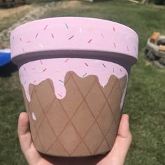 a hand holding up a cup with ice cream and sprinkles