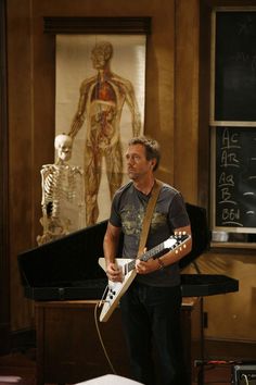 a man playing an electric guitar in front of a skeleton