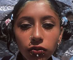 a woman with piercings on her nose and nose ring in front of a rock wall