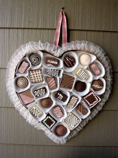 a heart shaped box filled with chocolates hanging on the wall next to a building