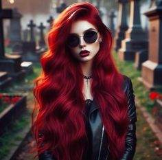 a woman with long red hair wearing sunglasses and a black leather jacket is standing in a cemetery