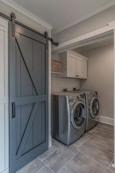 a washer and dryer in a laundry room with an open barn door that leads to the kitchen