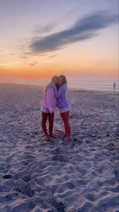 two girls hugging on the beach at sunset