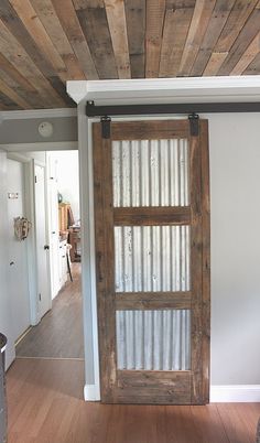 an open wooden door in a room with white walls and wood planks on the ceiling