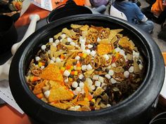 a black pot filled with corn chips and other food on top of a table next to a book