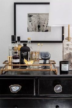 a black dresser with liquor bottles on it and a white lamp in the corner next to it