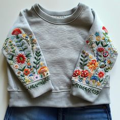 a sweater and jeans with embroidered flowers on them