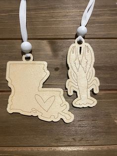 two wooden state shaped luggage tags on a wood background with white string and bead closures